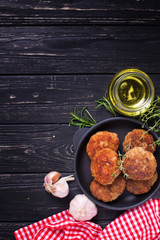 Homemade cutlets with herb and spices  on  black wooden background.