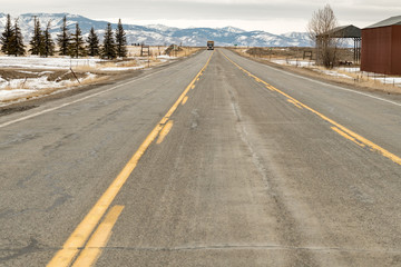 Eighteen wheeler on a mountain highway in winter with snow and pine trees