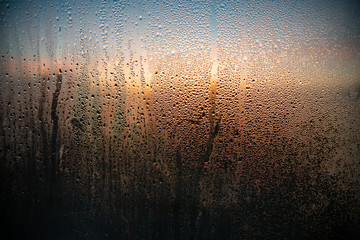 drops of water on the misted window. Outside the window a beautiful sunset