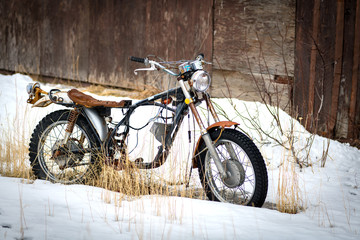 Old antique motorcycle parked in the snow winter time outside