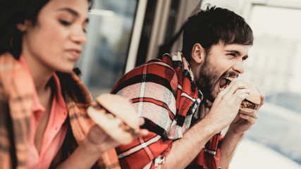 Young Couple in Checkered Plaids Eating Burgers.