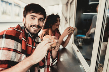 Young Couple in Checkered Plaids Eating Burgers.