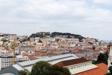 Fototapeta na wymiar View of the Lisbon from the viewpoint Miradouro de Sao Pedro de Alcantara. Sightseeing In Portugal. Orange roofs of the old town.