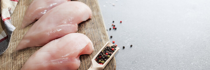 Raw chicken fillet with spices on light grey stone background. Place for text. Top view.
