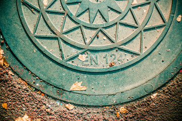 Close up to a half of a sewer cap. Top view of an iron manhole