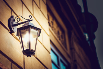 Vintage European design lantern hanged on wall at night while lit