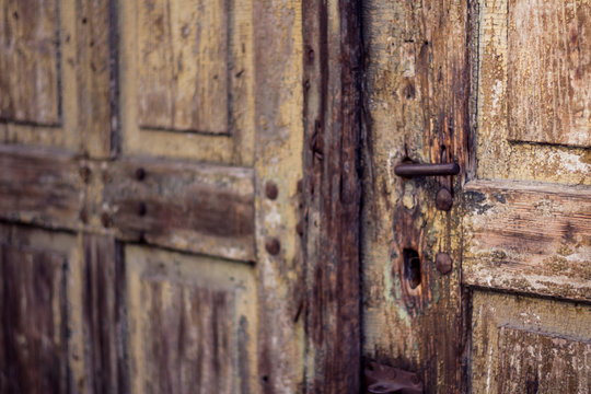 Old weathered antique wooden door with iron handle