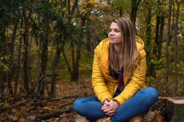 Naklejka premium A beautiful young blond-haired woman is thinking alone in the autumn forest