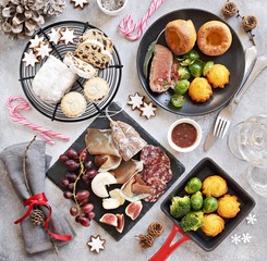 Christmas dinner table with roast beef,yorkshire pudding,appetizers platter and traditional cake. Christmass celebration, festive family dinner.  Overhead view.