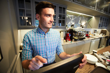 Young sales clerk standing by counter in front of computer and entering order information