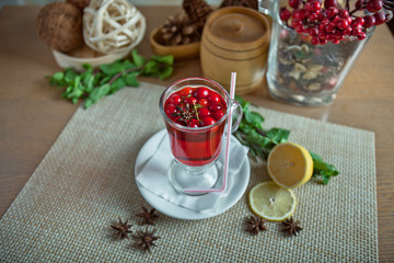 cranberry drink with a lemon on a wooden table in a glass service