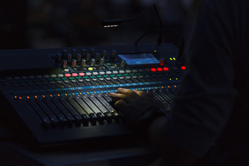 A man hand on a mixing console changing sound volume