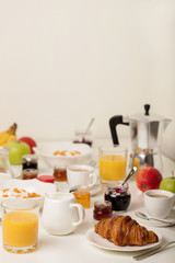 Breakfast time. Croissants and orange juice, jam and honey. Coffee with cream or milk. Fruits - bananas, red and green apples. Ricotta with sour cream, nuts and dried apricots.