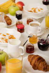Fototapeta na wymiar Breakfast time. Croissants and orange juice, jam and honey. Coffee with cream or milk. Fruits - bananas, red and green apples. Ricotta with sour cream, nuts and dried apricots.