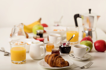 Breakfast time. Croissants and orange juice, jam and honey. Coffee with cream or milk. Fruits - bananas, red and green apples. Ricotta with sour cream, nuts and dried apricots.