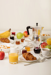 Breakfast time. Croissants and orange juice, jam and honey. Coffee with cream or milk. Fruits - bananas, red and green apples. Ricotta with sour cream, nuts and dried apricots.