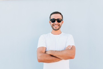 Sexy smiling handsome man with crossed arms on blue background