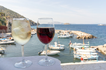 Glasses of wine on a white table, at an outdoor cafe overlooking the Kamini fishing village on the Greek Island of Hydra.