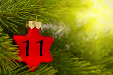ein Weihnachtsbaumanhänger (Stern) am Baum mit einer Zahl (11)