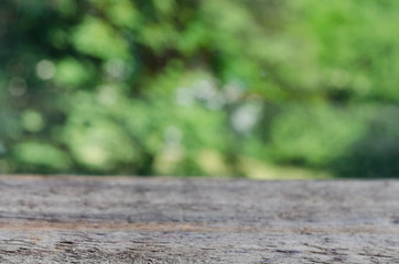 Empty wooden table over green nature blurred background. Copy space