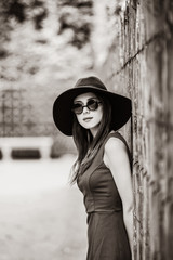 girl in sunglasses near fence in Versailles garden. Image in black and white color style