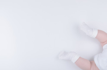 Baby lying on stomach in white bodysuit and socks. Copy space.