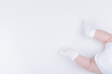Infant in white clothes lies on stomach