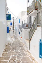 Traditional houses with blue doors and windows in the narrow streets of greek village in Mykonos, Greece