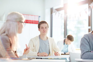 Confused guy looking at pretty groupmate showing him rude gesture at lesson