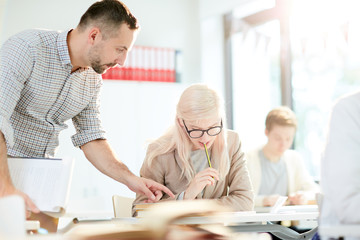 Obraz premium Confident teacher pointing at notes of girl sitting and looking at what she wrote