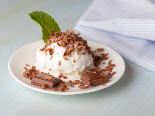 Ice cream with mint and chocolate in a saucer on a light table