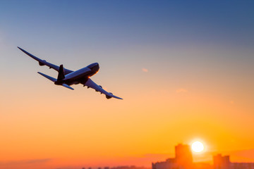 Airplane flying above in the sunset with skyscrapers. Transportation and travel, destination. Turn right.