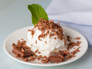 Ice cream with mint and chocolate in a saucer on a light table