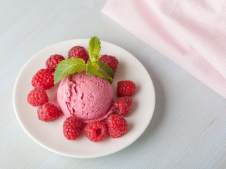 A raspberry ice cream with berries and mint leaves on a light background
