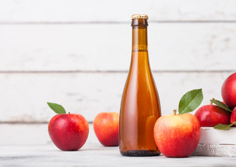Bottle and glass of homemade organic apple cider with fresh apples in box on wooden background