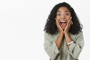 Portrait of upbeat enthusiastic and delighted surprised dark-skinned girlfriend with curly...