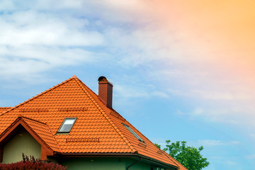 Close-up detail of new modern house top with shingled red roof, high chimney, attic windows on...