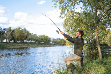 Man with rod fishing at riverside. Recreational activity