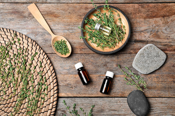 Flat lay composition with natural essential oil and thyme on wooden background