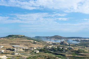 Fototapeta na wymiar Smoke bellowing in the agricultural countryside of Gozo Island, Malta