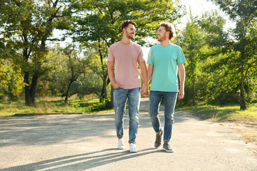 Happy gay couple walking in green park