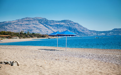 Fototapeta na wymiar two blue umbrellas on a beach
