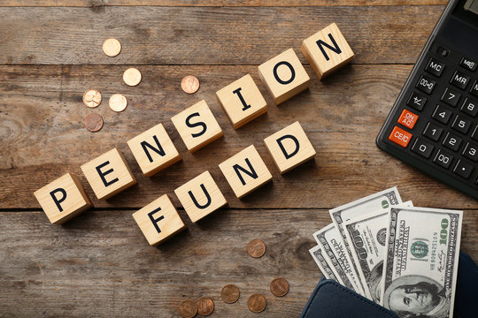 Flat lay composition with words "PENSION FUND", money and calculator on wooden background