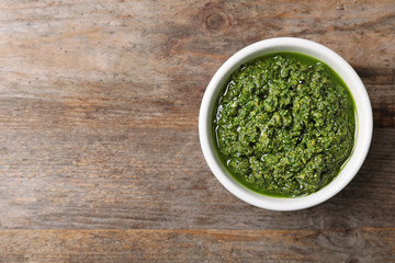 Homemade basil pesto sauce in bowl and space for text on wooden table