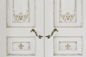 Large white door closed and vintage metal handles.