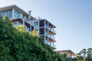 Fototapeta na wymiar Modern luxury apartment building against blue sky and bushes