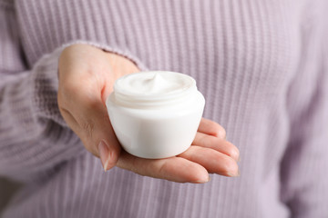 Woman holding jar of moisturizing cream, closeup. Winter skin care cosmetic