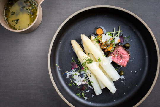 Modern Style classic white asparagus with barbecue dry aged sliced beef fillet and vegetable served as top view on a minimalistic design plate