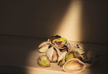 Dry salted pistachios (Pistacia vera) on a wooden table. Sunlit.