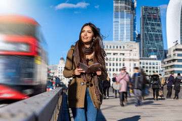 Obraz premium Attraktive Touristin in London auf Sightseeing Tour mit einem Reiseführer in der Hand